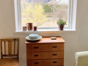 A room with a wooden dresser, a window with a view of trees and a fence, and a small potted plant on the windowsill. - 6 Person Holiday Home in Mellbystrand (Mellbystrand)