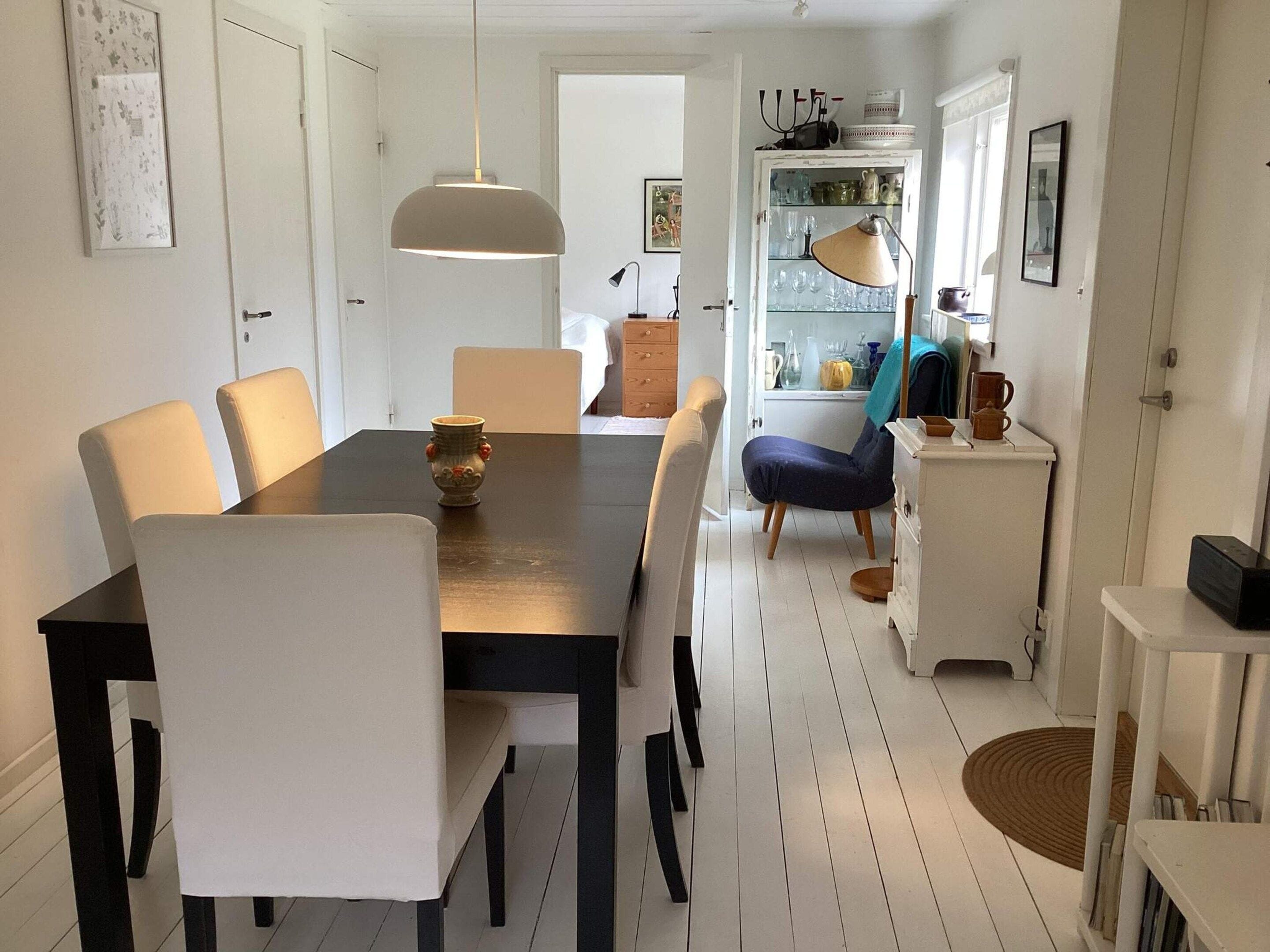 Un coin repas comprenant une table, des chaises, un vase et un buffet contenant de la verrerie.