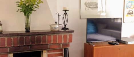 A living room with a brick fireplace, a television, and a wooden cabinet.