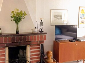 A living room with a brick fireplace, a television, and a wooden cabinet. - 6 Person Holiday Home in Mellbystrand (Mellbystrand)