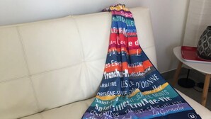 A white leather sofa with a colorful blanket featuring French town names. - Very comfortable single-storey house 2 minutes from the ocean on the island of Noirmoutier (L'EPINE)