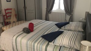 A bedroom with a bed, a wardrobe, a chair, and a window with curtains. - Very comfortable single-storey house 2 minutes from the ocean on the island of Noirmoutier (L'EPINE)