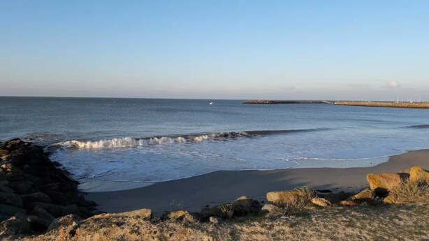 A coastal beach scene with waves, rocks, and a distant pier. - Very comfortable single-storey house 2 minutes from the ocean on the island of Noirmoutier (L'EPINE)