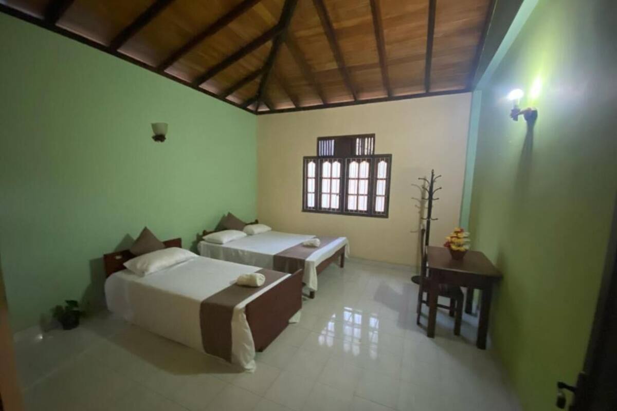 A room with two beds, a window, a chair, and a table.