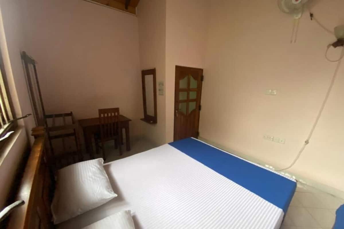 A room with a bed, a chair, a desk, and a mirror.