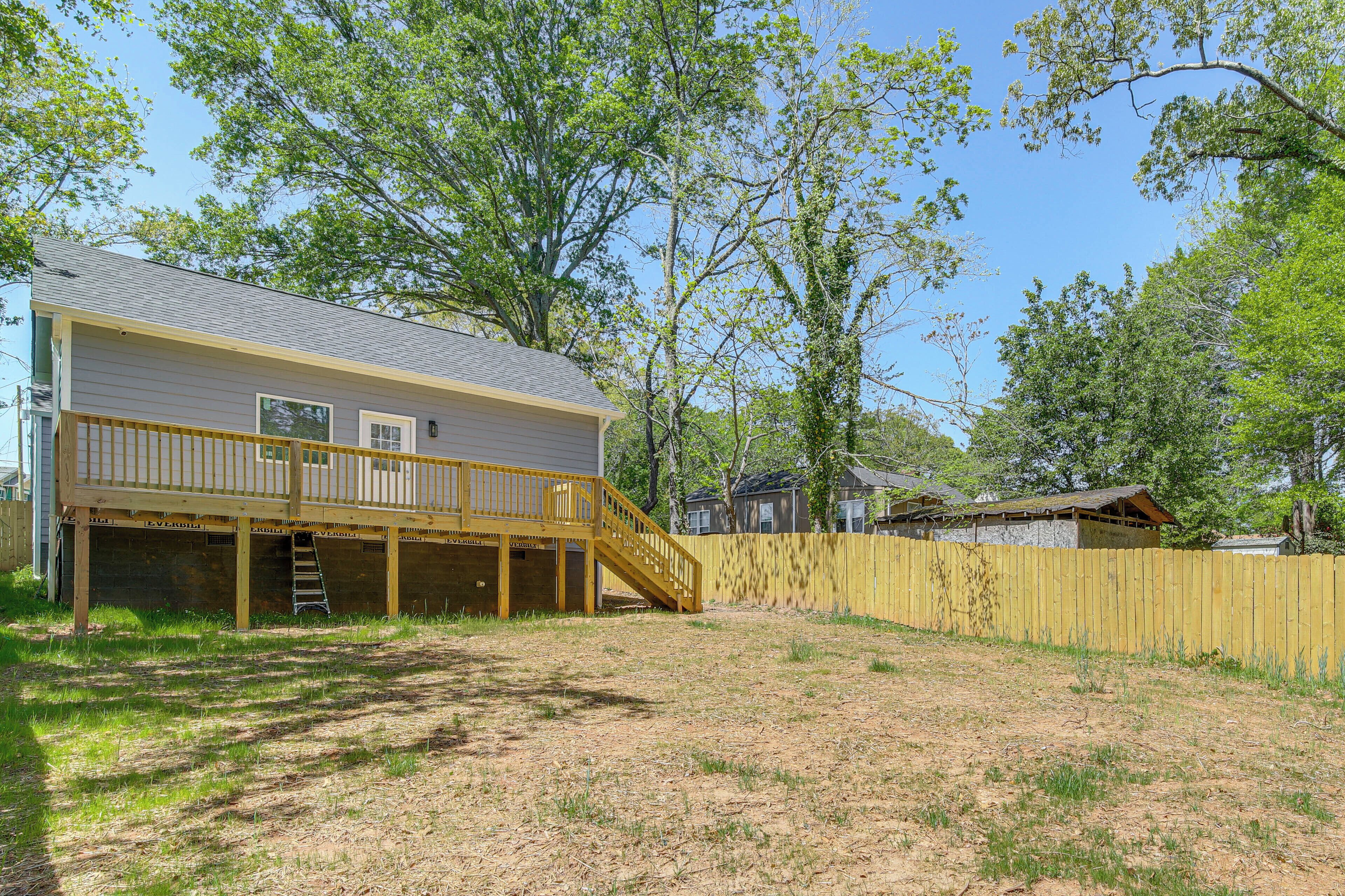 A two-story house with a wooden deck and a staircase leading to a covered area.