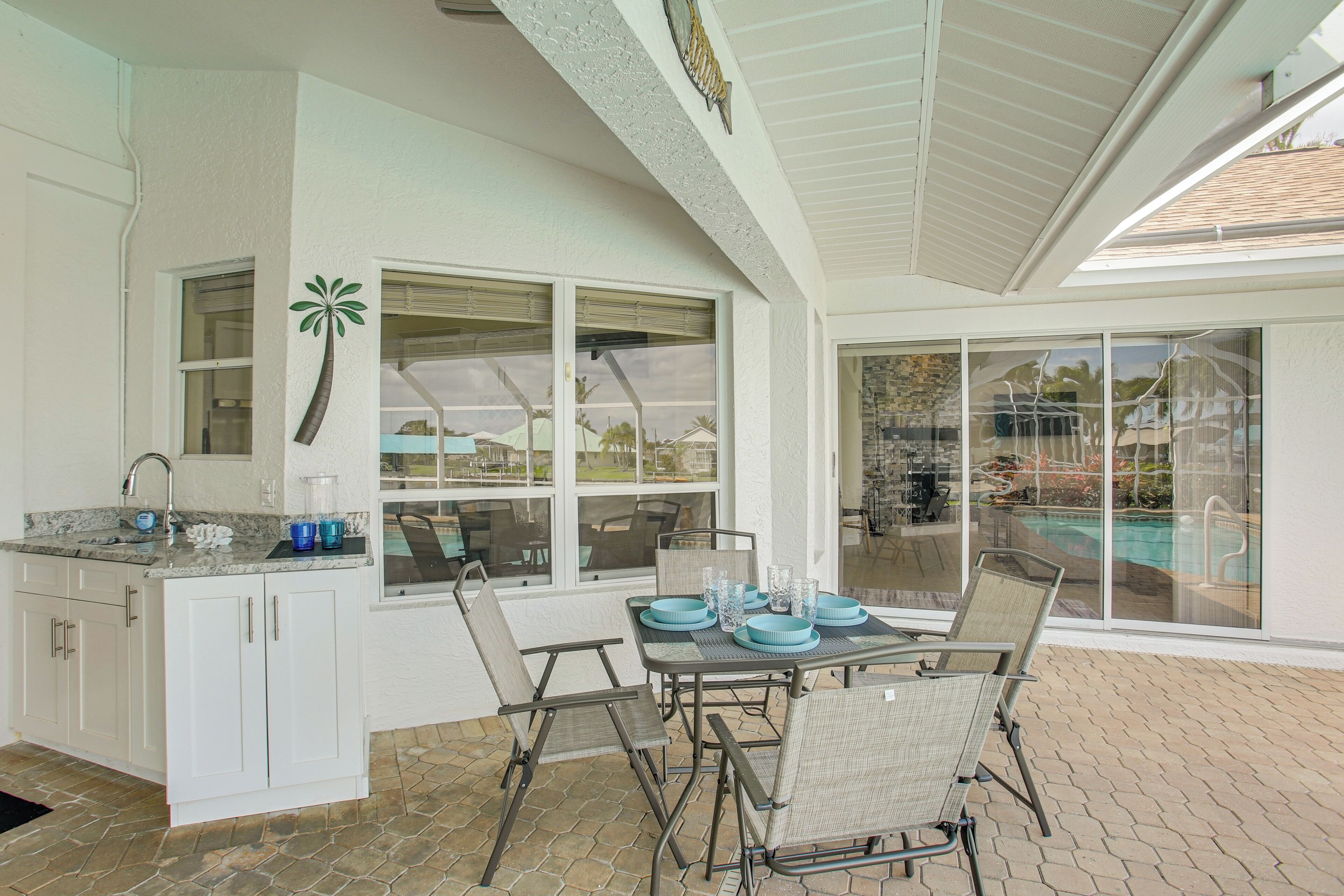 A kitchen with a dining area, large windows, and a view of a swimming pool.