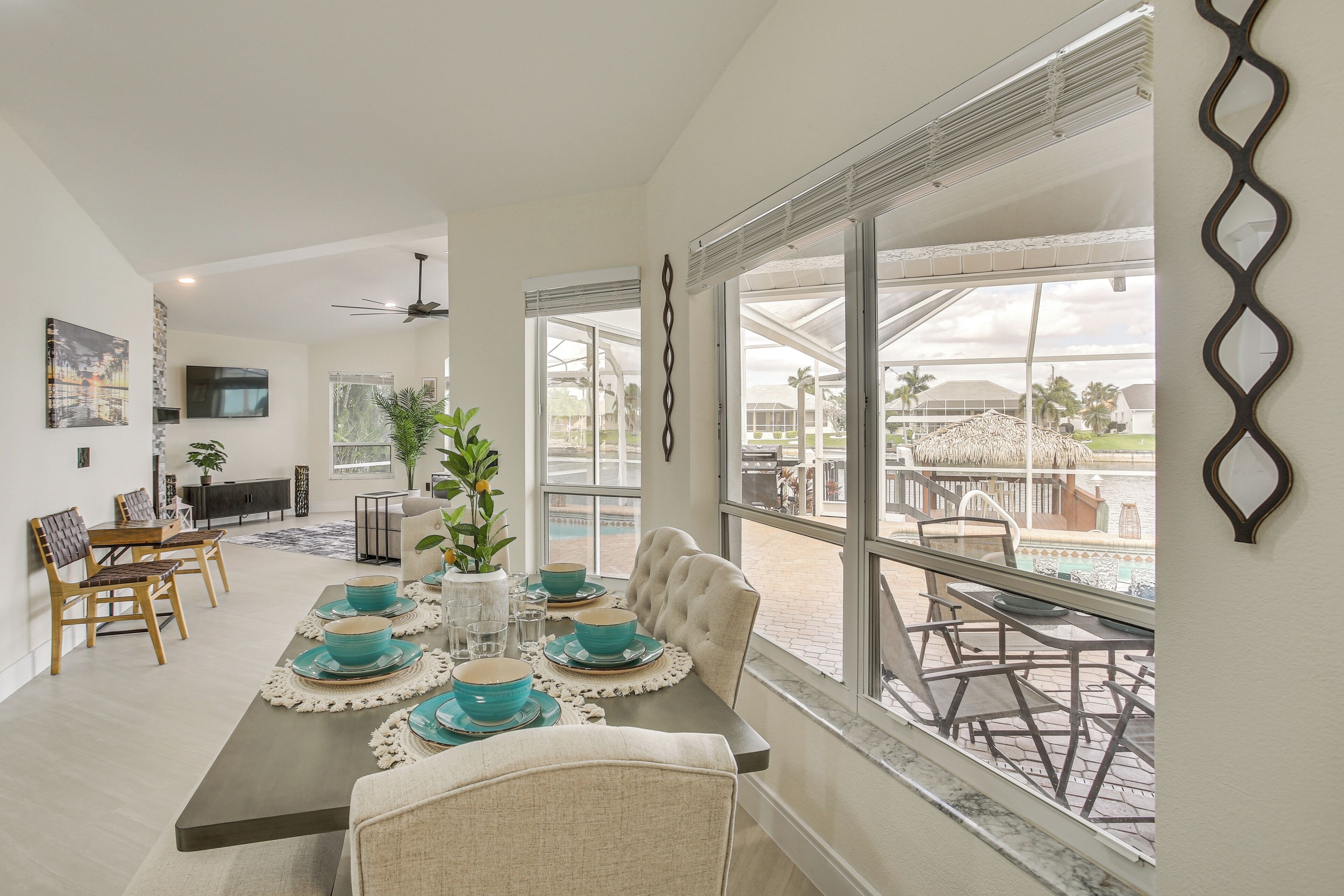 A dining area with a table set for four, a ceiling fan, and a view of the outdoor pool area.