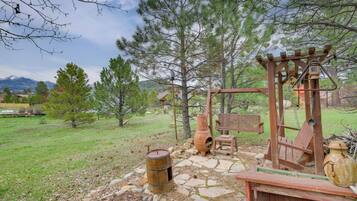 A rustic outdoor setting with a wooden swing set, a stone pathway, and a wooden bench.