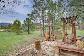 A rustic outdoor setting with a wooden swing set, a stone pathway, and a wooden bench. - Walk to Trails! Pagosa Home w/ Patio + Views (Pagosa Springs)
