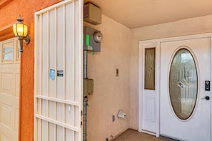 A gated entrance with a white door, a utility box, and a wall-mounted light fixture. - ABQ Townhouse w/ Mtn-view Balcony: Pets Welcome! (Albuquerque)