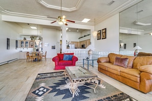 A spacious living area with a red sofa, a brown leather couch, a glass coffee table, and a patterned rug. - ABQ Townhouse w/ Mtn-view Balcony: Pets Welcome! (Albuquerque)