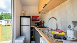 A compact kitchen with a built-in refrigerator, a microwave, a sink, and a stove. - Nature-rich Caravan Retreat for 6 (Kaprijke)