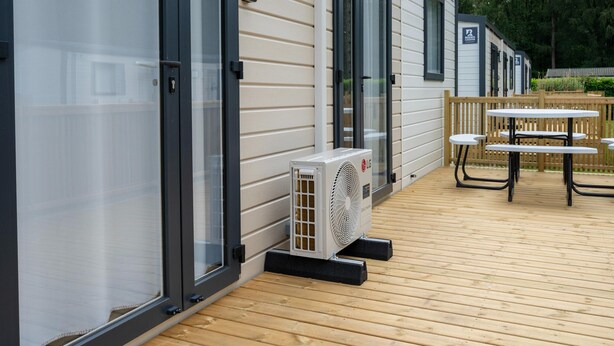 A mobile home with a patio, outdoor seating, and an air conditioning unit. - Nature-rich Caravan Retreat for 6 (Kaprijke)