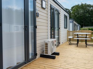 Una casa móvil con un patio, mobiliario exterior y un equipo de aire acondicionado.