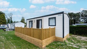 A mobile home with a fenced yard, a window, and a door. - Nature-rich Caravan Retreat for 6 (Kaprijke)