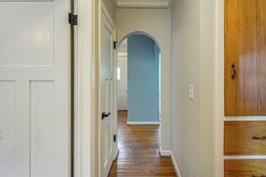 Um corredor com piso de madeira, portas brancas e parede azul.