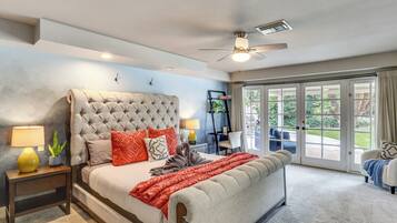 A bedroom with a large bed, a ceiling fan, and a view through a sliding glass door.