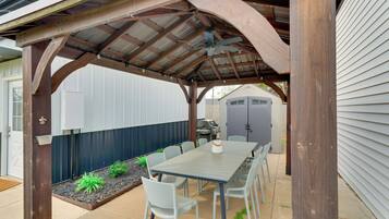 A covered patio with a table and chairs, a ceiling fan, and a grill area.