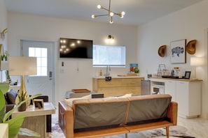 A modern living room with a sofa, a TV, a dining area, and a kitchen. - 1 Mi to OU! Sleek Guest House w/ Gas Grill (Norman)