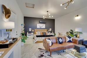 Un salon moderne avec un canapé, une table basse et un coin repas équipé d’une machine à café.