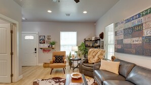 A living room with a leather sofa, a cowhide rug, a small table, and a wall with license plates. - Walk to Norman Hot Spots: Family-friendly Home! (Norman)