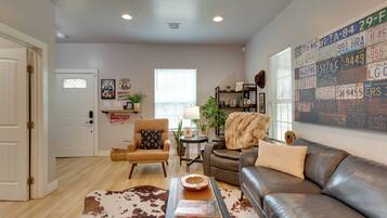 A living room with a leather sofa, a cowhide rug, a small table, and a wall with license plates.