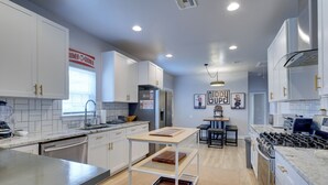 A modern kitchen with white cabinets, a built-in oven, a gas stove, and a dining area with a table and chairs. - Walk to Norman Hot Spots: Family-friendly Home! (Norman)