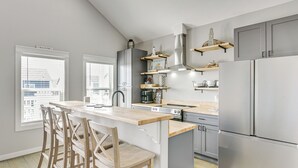 Uma cozinha moderna com uma ilha central, banquetas, eletrodomésticos de aço inoxidável e prateleiras embutidas.