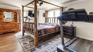 Ein Schlafzimmer mit Himmelbett, Laufband, einem Holzschrank und einem an der Wand montierten Fernseher.