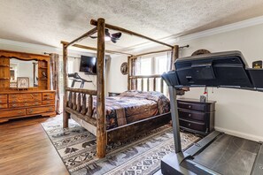 Ein Schlafzimmer mit Himmelbett, Laufband, einem Holzschrank und einem an der Wand montierten Fernseher.