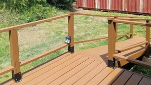 Eine Holzterrasse mit Geländern und einer Laterne.