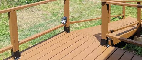 Una terraza de madera con barandas y un farol.