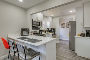 A modern kitchen with white cabinetry, a central island, and a seating area with chairs. - 'the Red Door' Stylish Family Home in Falls Church (Falls Church)