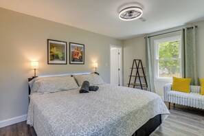 A bedroom with a bed, two wall-mounted lamps, a ladder, a window with curtains, and a radiator.