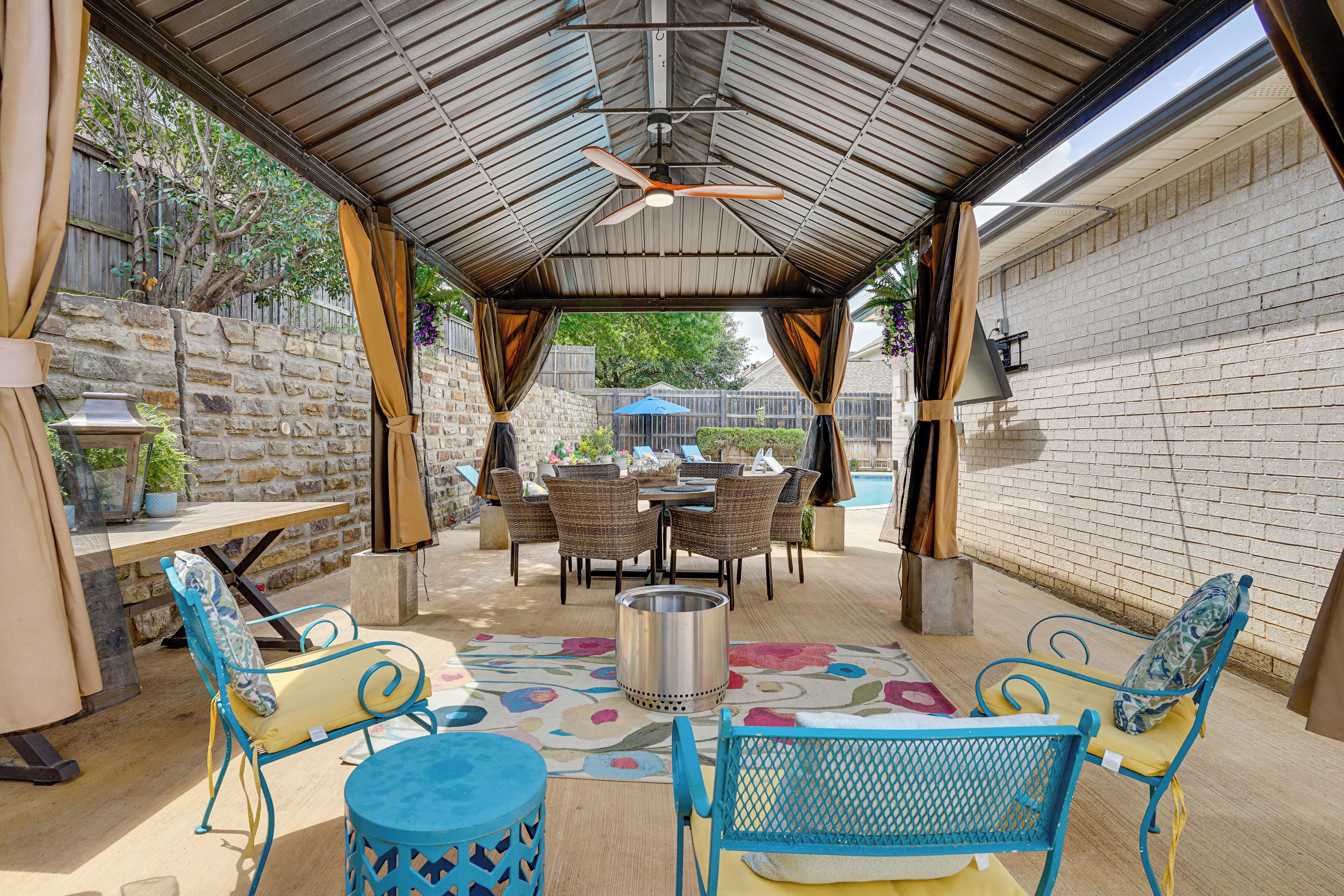 An outdoor patio with a covered seating area, a table, and a ceiling fan.