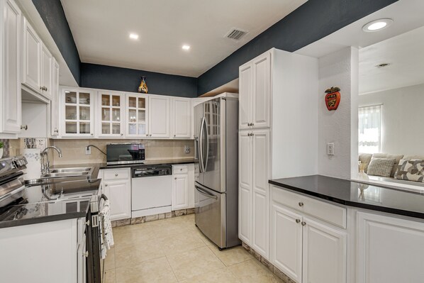 A modern kitchen with white cabinetry, stainless steel appliances, and a black countertop. - 4 Mi to Hard Rock Stadium & Lakes! Elegant Home (Opa-Locka)