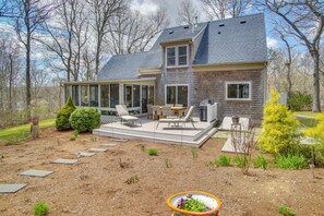 Ein modernes, zweistöckiges Haus mit Terrasse, Gartenmöbeln und Garten.