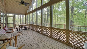 A covered outdoor area with wooden flooring, tables, benches, and a view of a forest through large windows. - 3 Mi to Marina on Dale Hollow Lake! Cabin Getaway (Byrdstown)