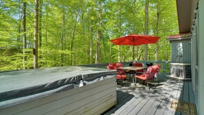 A deck with a hot tub, red chairs, and a table with a red umbrella. - Dale Hollow Hideaway! Cabin w/ Hot Tub (Byrdstown)