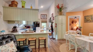 A kitchen with a central island, bar stools, a dining table with chairs, and a living area with a sofa. - Dale Hollow Hideaway! Cabin w/ Hot Tub (Byrdstown)