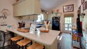 A kitchen with a central island, bar stools, and a refrigerator. - Dale Hollow Hideaway! Cabin w/ Hot Tub (Byrdstown)