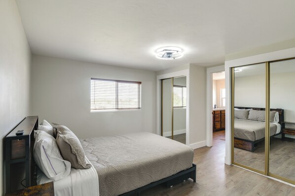 Quarto com cama, mesa de cabeceira, janela e espelho.