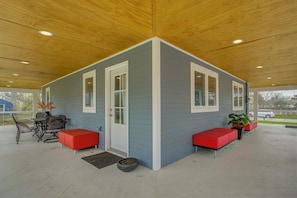 A covered patio with a blue exterior, white trim, and red seating. - < 1 Mi to Oakland University: Cozy Retreat w/ Yard (Auburn Hills)
