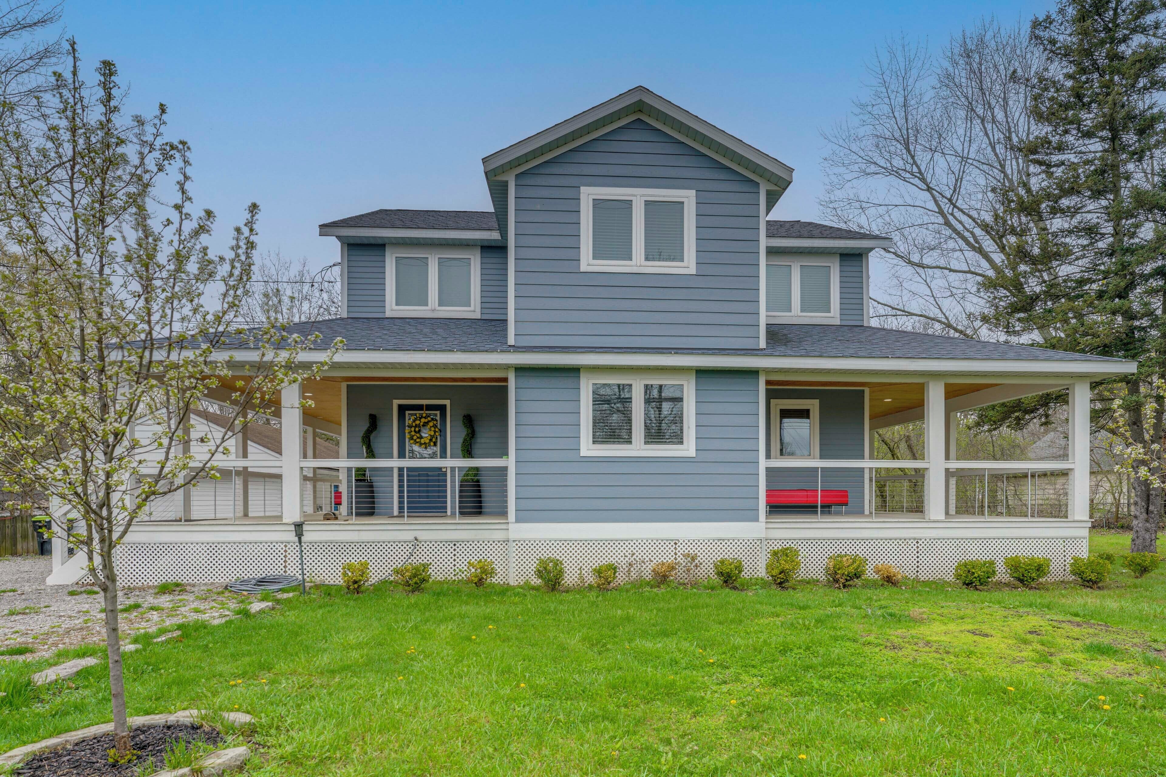 A two-story house with a covered porch, a small front yard, and a clear sky.