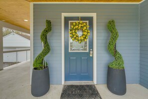 A blue door with a yellow wreath, two potted plants, and a welcome mat. - < 1 Mi to Oakland University: Cozy Retreat w/ Yard (Auburn Hills)