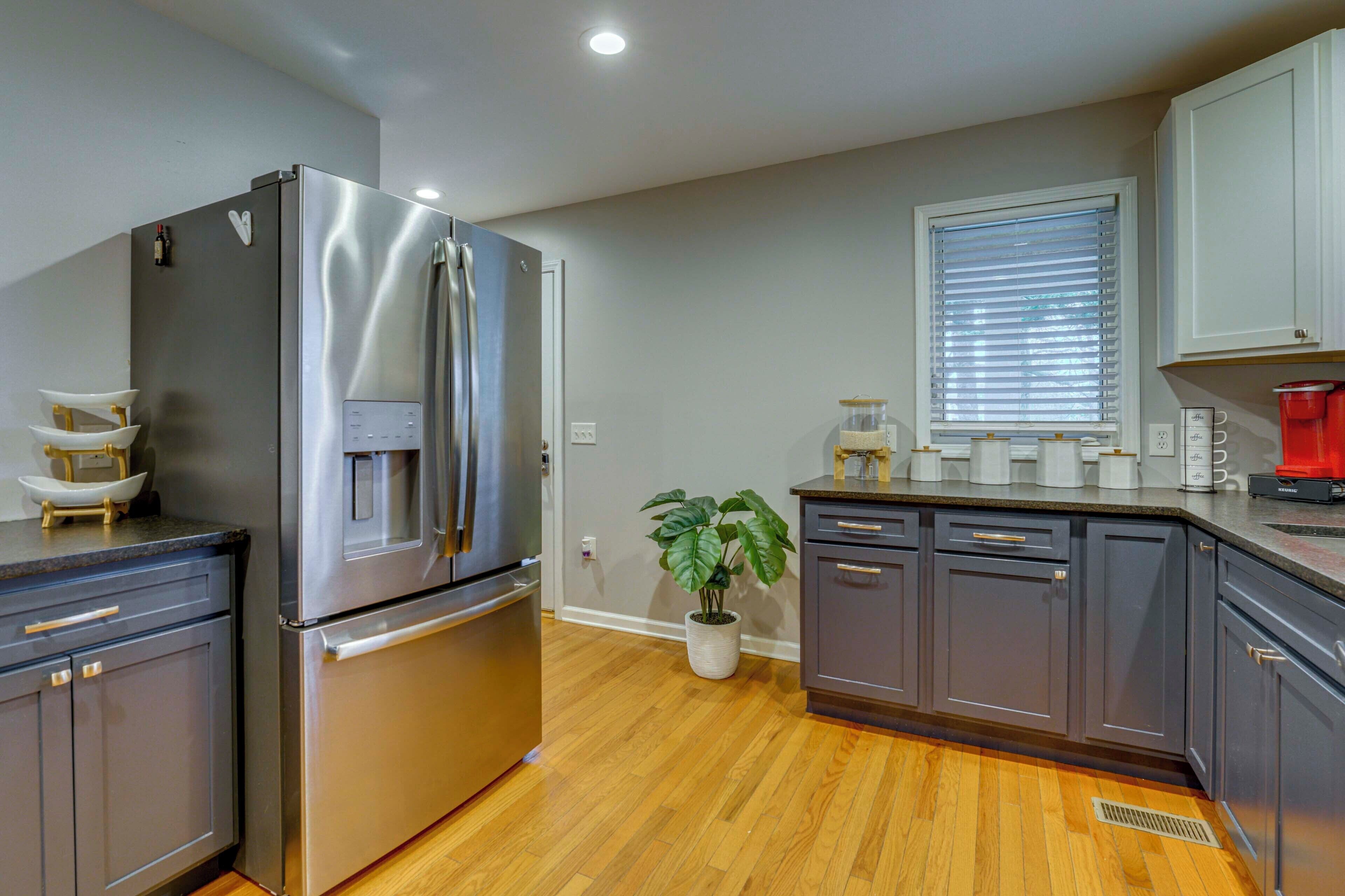 A modern kitchen with stainless steel appliances, wooden flooring, and a potted plant.