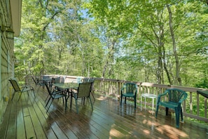 Eine Holzterrasse mit Gartenmöbeln, umgeben von Bäumen.