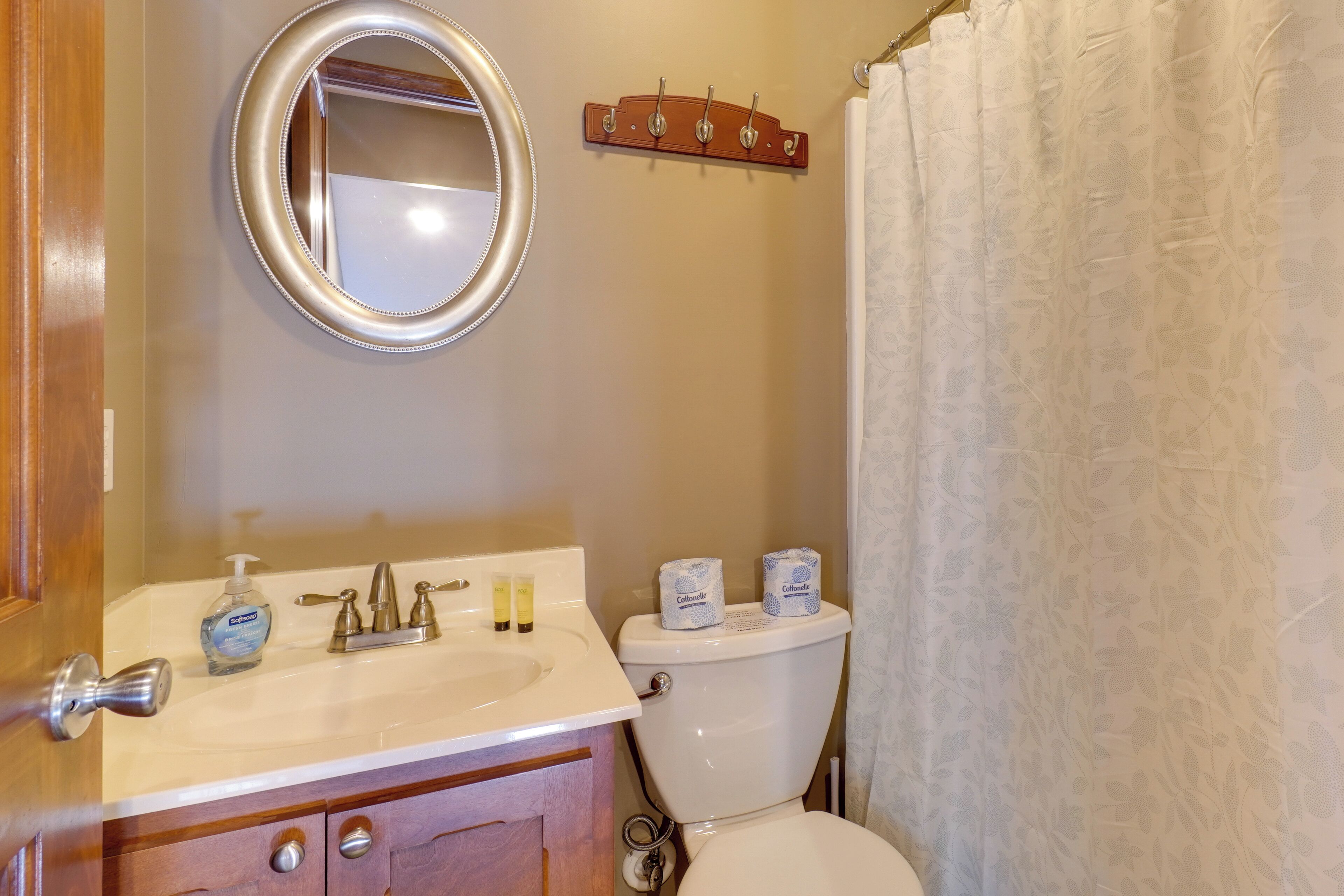A bathroom with a sink, mirror, toilet, and a towel rack.