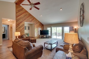 A living room with a herringbone wood ceiling, a ceiling fan, a flat-screen TV, leather sofas, a coffee table, and a lamp. - 'mountain View' Home Near Dale Hollow Lake Fun! (Byrdstown)